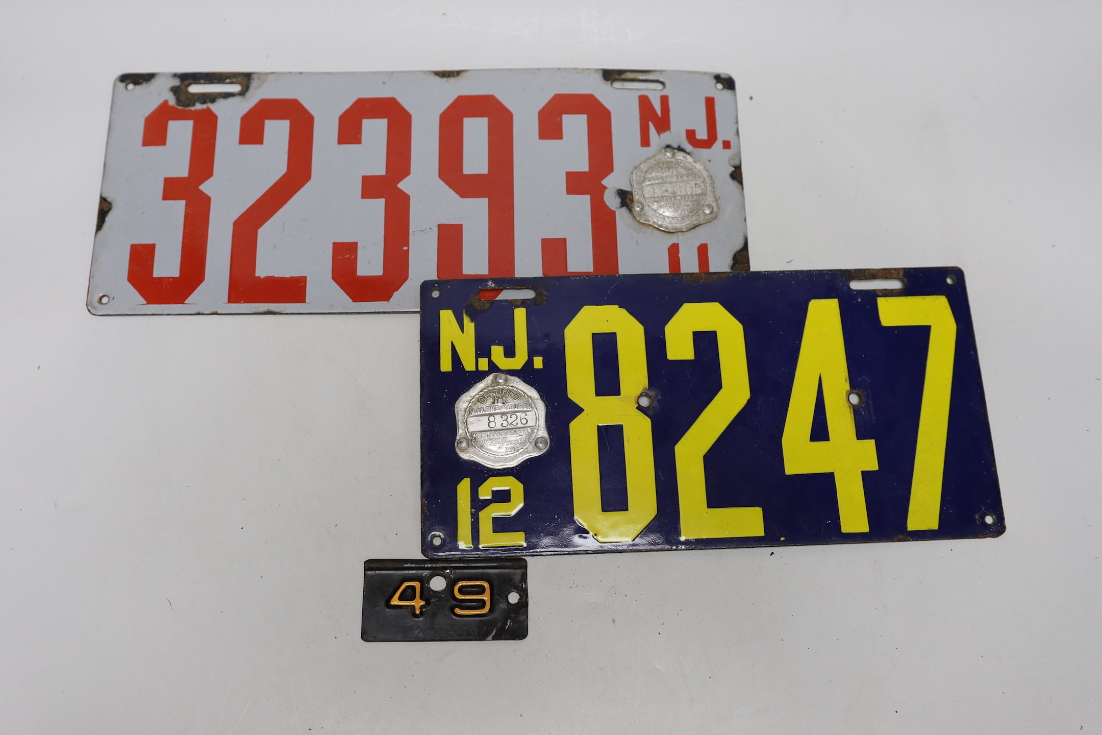 Eight New York and other car number plates, with badges attached